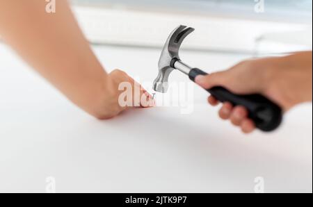 Nahaufnahme der Hände, die zu Hause Nagel an die Wand schlagen Stockfoto