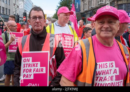 Belfast, Großbritannien. 31. August 2022. Männer mit Schildern, die mit anderen Aktivisten streiken, versammelten sich vor dem Rathaus von Belfast, um angesichts der steigenden Lebenshaltungskosten während der NI Strike Rally der Communication Workers Union für eine bessere Bezahlung zu plädieren. Quelle: Steve Nimmons/Alamy Live News Stockfoto