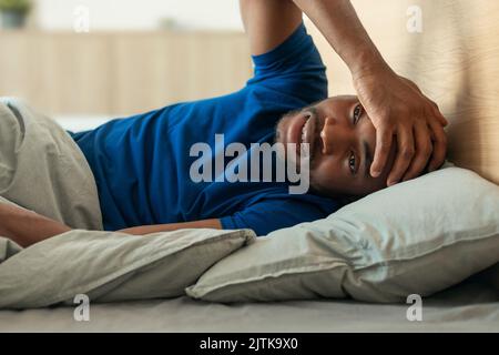 Schwarzer Mann, Der Den Kopf Berührt Und Schlaflosigkeit Und Kopfschmerzen Hat Stockfoto