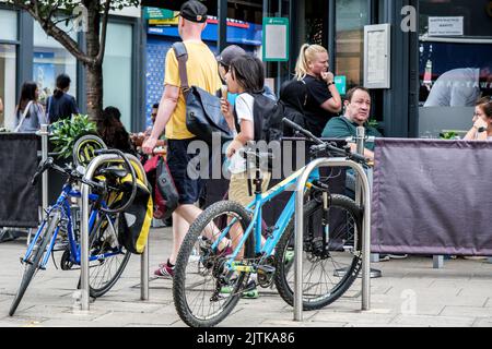 Kingston-upon-Thames, London, Großbritannien, August 29 2022, Menschen, die an Einem Restaurant vor dem Sitzbereich mit geparkten Fahrrädern auf dem Bürgersteig vorbeigehen Stockfoto