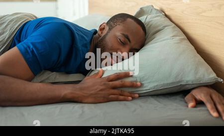 Afroamerikanischer Mann Schläft Friedlich Umarmt Kopfende Im Schlafzimmer Liegend Stockfoto