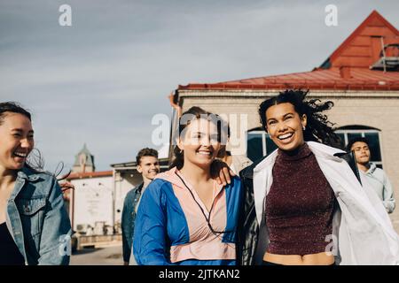 Glückliche multirassische junge Frauen mit Freunden genießen in der Stadt Stockfoto