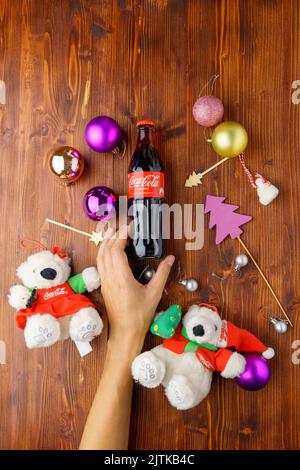 Tjumen, Russland-30. August 2022: Coca-Cola Classic in einer Glasflasche mit Weihnachtsbaumschmuck, Geschenken und Bällen. Flach liegend. Vertikales Foto Stockfoto