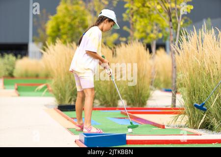 Schöne kleine Mädchen spielen Mini Golf Stockfoto