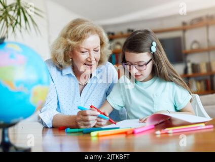 Hausaufgaben Unterricht Bildung Großmutter Kinder Enkelin Familie Kindheit Kind Lehrer Klassenzimmer Senior Farbe Färbung Malerei Buch Notizbuch Stockfoto