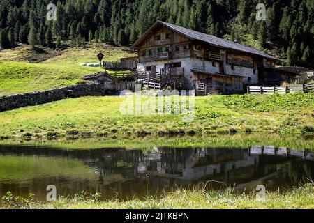Traditionelles Holzhaus in der Nähe eines Teiches in der Seebachalm im Defereggental in den österreichischen alpen in Osttirol, Österreich Stockfoto