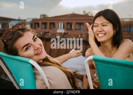 Porträt glücklicher Frauen, die bei Sonnenuntergang auf einem Stuhl sitzen Stockfoto