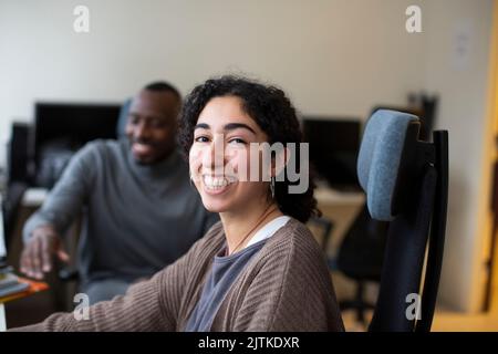 Porträt einer glücklichen Geschäftsfrau, die mit einem Kollegen im Büro sitzt Stockfoto