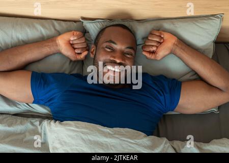 Glücklicher Schwarzer Mann Erwacht Nach Dem Schlaf Stretching Liegend Im Schlafzimmer Stockfoto