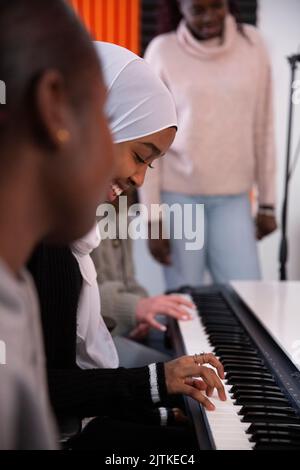 Lächelndes Mädchen, das im Aufnahmestudio Klavier spielt Stockfoto