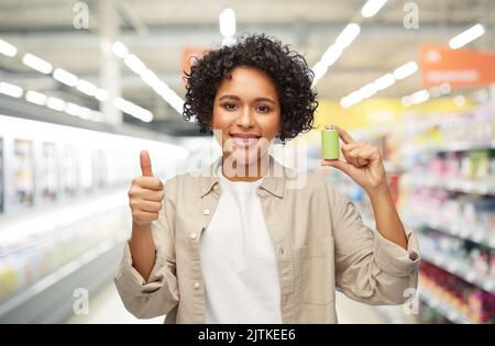 Lächelnde Frau mit Alkalibatterie im Supermarkt Stockfoto