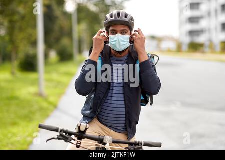 Lieferung Mann in Maske mit smatphone Fahrrad fahren Stockfoto