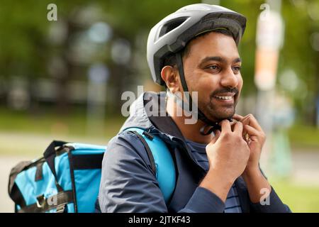 Lebensmittel Lieferung Mann Befestigung Fahrradhelm in der Stadt Stockfoto