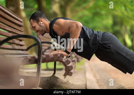 Glücklich schwarz Kerl Sportler tun Liegestützen im öffentlichen Park Stockfoto