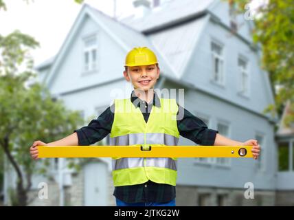 Junge im Bau Helm und Weste mit Niveau Stockfoto