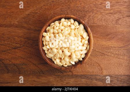 Holzschüssel mit Wachsbohnen auf Holzhintergrund. Draufsicht. Haarentfernung, Enthaarung. Stockfoto