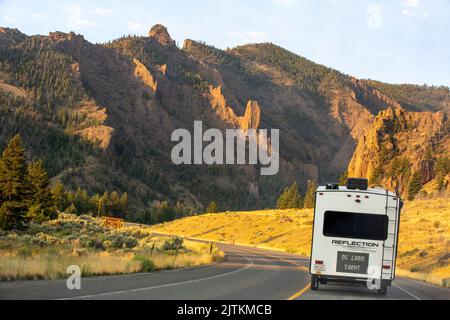 Ein Wohnmobil-Anhänger auf einem Highway bei Sonnenaufgang in den Absaroka Mountains, der entlang der North Fork des Shoshone River fuhr, führte zum Yellowstone Park. Stockfoto