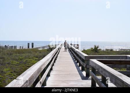 Ein Mann, der auf einer hölzernen Promenade in der Nähe des Meeres steht Stockfoto