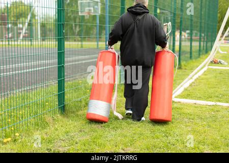 Sportgeräte für das Training. Trainer trägt Birnen zum Boxen. Sportgeräte in roter Farbe. Details zur Vorbereitung des Sportwettbewerbs. Stockfoto
