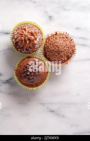 Von oben auf grauem Marmorhintergrund gedrehte Cupcakes aus Schokolade mit Platz für Kopien Stockfoto