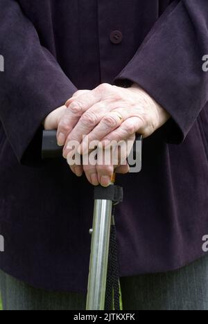 Nahaufnahme der Hände älterer Frauen, die auf einem Spazierstock ruhen Stockfoto