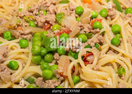 Pasta, Hackfleisch, Erbsen, grüne Paprika und gehackte Tomaten über einer Pfanne in Brasilien. Stockfoto