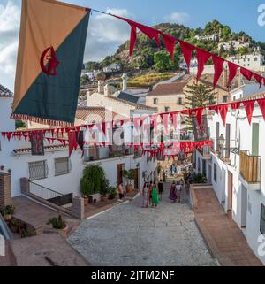 Frigiliana, Malaga, Spanien, 27. August 2022: Blick auf die Straße von Frigiliana mit einem Banner und Girlande anlässlich der drei Kulturen festlich geschmückt Stockfoto