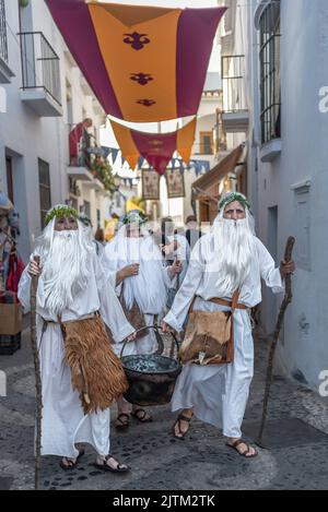 Frigiliana, Malaga, Spanien, 27. August 2022: Druiden, die als Zauberer mit Bärten und weißen Gewändern gekleidet sind und einen Kessel durch die Straßen von Frigiliana tragen Stockfoto