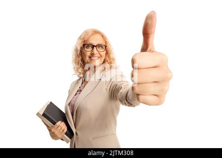 Reife Lehrerin, die Bücher hält und Daumen hoch zeigt, isoliert auf weißem Hintergrund Stockfoto