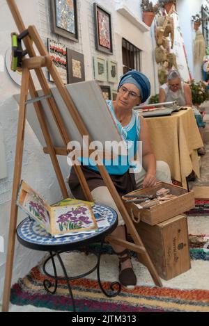 Frigiliana, Malaga, 27. August 2022: Mosaikkünstlerin, die auf einer Straße in Frigiliana anlässlich des Festivals der drei Kulturen arbeitet Stockfoto