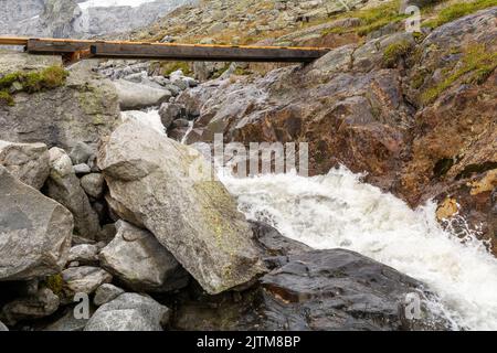 Eine kleine Holzbrücke über einen wilden Alpenfluss Stockfoto
