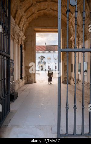 Campus der Universität Coimbra. Student von hinten gesehen am Ende eines schmalen Korridors zur Campus University of Coimbra in Portugal. Stockfoto