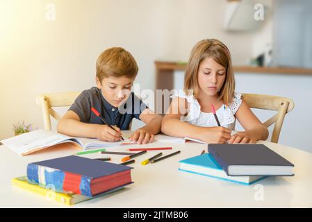 Kinder, die sich auf Zeichnen und Studieren zu Hause konzentrieren. Kinder machen Hausaufgaben im Klassenzimmer. Zurück zur Schule Stockfoto
