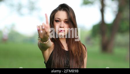 Verärgerte attraktive Frau, die mit Hand und Finger zurückweist und dem Betrachter NEIN sagt, sie verteidigt den Stand Stockfoto