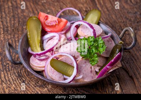 bayerischer Wurstsalat auf dunklem Holz Stockfoto