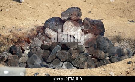 Heiße Kohlen und Steine schwelen, als die imu für ein Luau auf Hawaii vorbereitet wird. Stockfoto