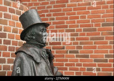 bronse-Statue des dänischen Schriftstellers H C Andersen im Profil gegen eine rote Mauer, Odense, Dänemark, 28. August 2022 Stockfoto