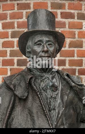 bronse-Statue des dänischen Schriftstellers H C Andersen in einem Zylinderhut vor einer roten Mauer, Odense, Dänemark, 28. August 2022 Stockfoto