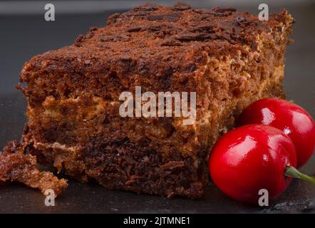 Kuchen und Kirsche auf dunklem Steingrund Stockfoto