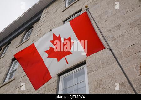 Kanadische Flagge an einem Gebäude befestigt und wehend im Wind, Ottawa, Ontario, Kanada. Stockfoto