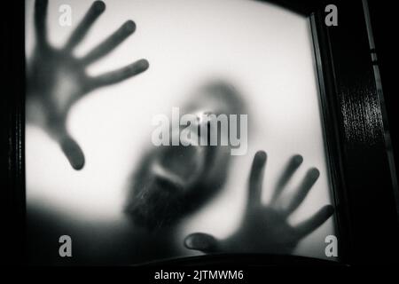 Gruseliges Bild von Händen hinter Glas, Horror-Geist hinter der Tür, Halloween-Konzept Stockfoto