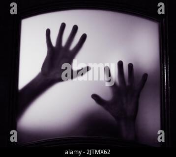 Gruseliges Bild von Händen hinter Glas, Horror-Geist hinter der Tür, Halloween-Konzept Stockfoto