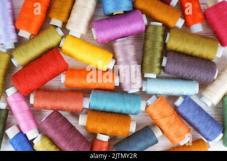 Streuung von verschiedenen Farben Nähfäden auf weißem Holzhintergrund. Flach liegend, Draufsicht. Stockfoto