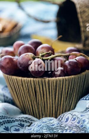Korbkorb voll roter Trauben. Picknick im Freien Stockfoto