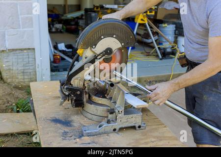 Der Arbeiter verwendet eine Gehrungsäge, um das Eisenrohr zu schneiden Stockfoto