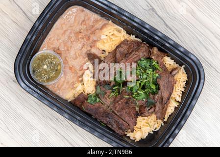 Die Ansicht der Ranchera mit Reis und Bohnen zum Mitnehmen ist bequem in einem mikrowellengeeigneten Behälter verpackt. Stockfoto