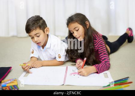 Diese Geschwister machen alles zusammen. Ein süßer kleiner Junge und seine Schwester färben sich zu Hause zusammen ein. Stockfoto