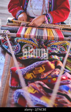 Indigene Frau zeigt traditionelle Webtechnik und Textilherstellung in den Anden in Südamerika in Peru, selektiver Fokus. Stockfoto