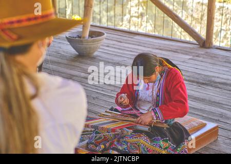 Indigene Frau zeigt traditionelle Webtechnik und Textilherstellung in den Anden in Südamerika in Peru, selektiver Fokus. Stockfoto