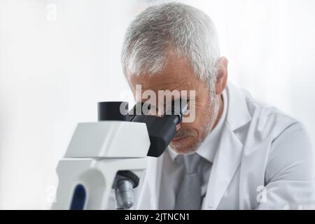 Der Schwerpunkt liegt auf der wissenschaftlichen Entdeckung. Ein Forscher bei der Arbeit an einem Mikroskop in einem Labor. Stockfoto